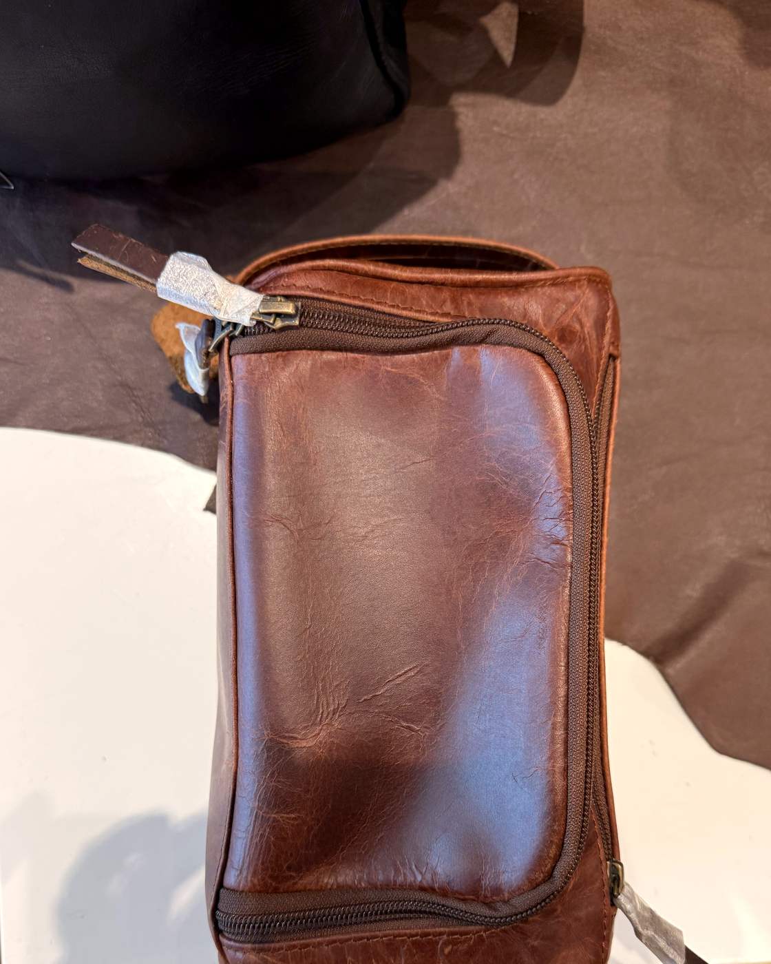 Real photo from above of the dopp kit, showing the crazy-horse leather, the main zip curving around the lid and the front zip pocket.