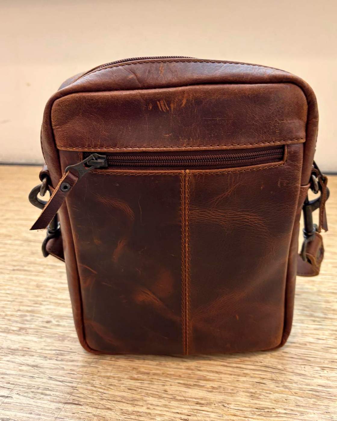 Real photo of the YYZ Satchel from the other side, showing a horizontal zipped pocket below the top panel and a vertical seam running down the centre of the panel.