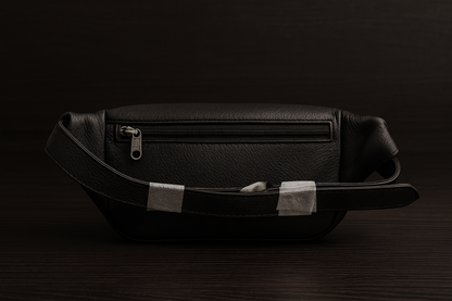 Black leather bag with silver zippers on a dark background