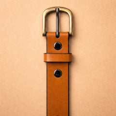 Bellvari Buckhorn honey-tan full-grain leather belt in natural light, antique-brass buckle and black domed rivets. — view 4