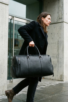 A woman carrying the black Bellvari Weekender leather duffel. — view 12