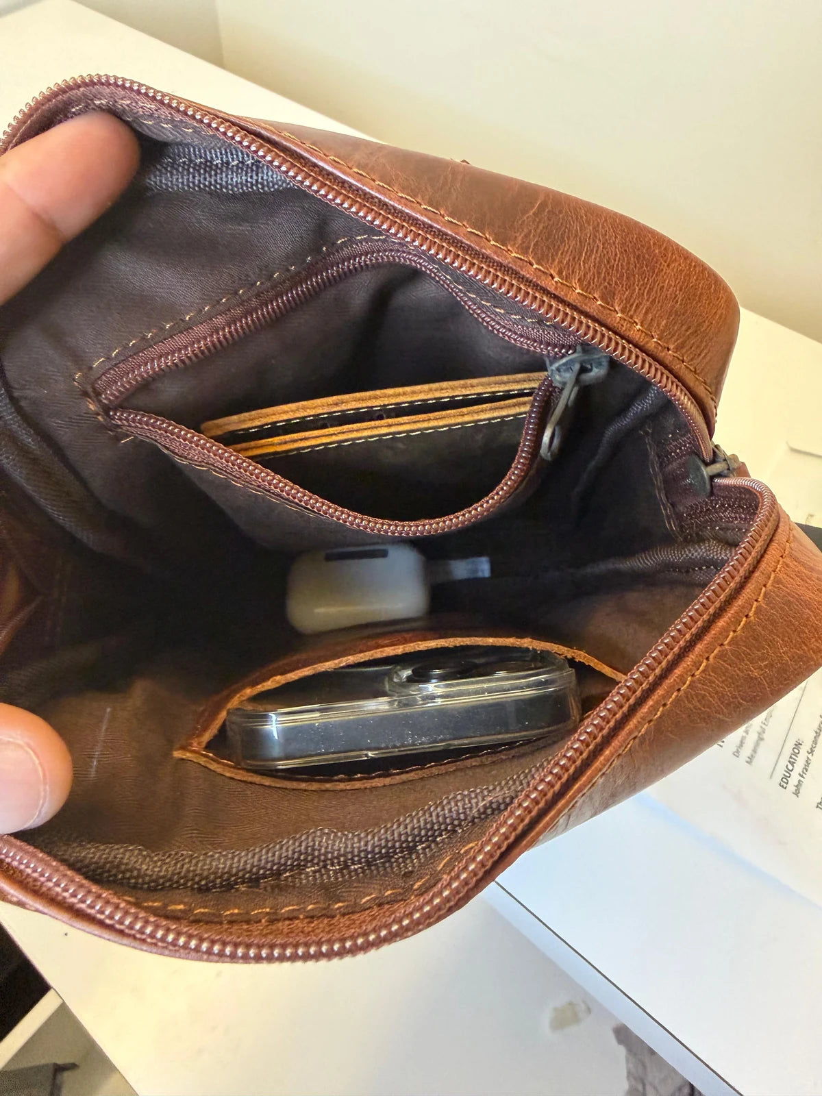 Real photo inside the Crazy Horse Brown YYZ Satchel, with a wallet in the open lining zip pocket and a phone in the opposite leather pouch.